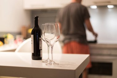 Masada iki kadeh şarap ve bir şişe beyaz bir adamın arka planına karşı sıcak bir atmosferde akşam yemeği hazırlıyor.