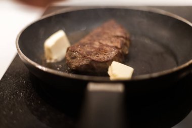 Biberiyeli ve tereyağlı tavada biftek pişirme süreci.