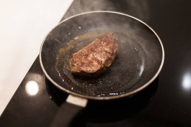 Biberiyeli ve tereyağlı tavada biftek pişirme süreci.