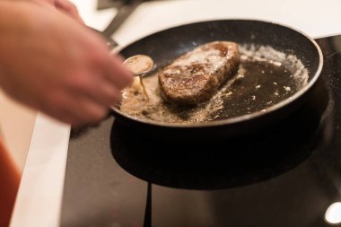 Biberiyeli ve tereyağlı tavada biftek pişirme süreci.