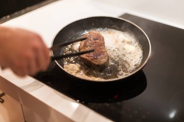 Biberiyeli ve tereyağlı tavada biftek pişirme süreci.