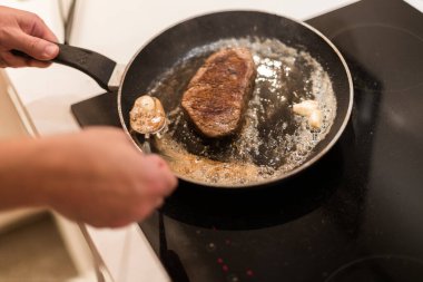 Biberiyeli ve tereyağlı tavada biftek pişirme süreci.