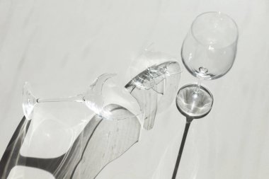 Kırık şarap kadehi, gölgeli minimalizmin beyaz arka planının yanında. Minimalizmin gölgeli beyaz arka planının yanında yüksek kaliteli fotokırık şarap kadehi.
