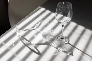 Kırık şarap kadehi, gölgeli minimalizmin beyaz arka planının yanında. Minimalizmin gölgeli beyaz arka planının yanında yüksek kaliteli fotokırık şarap kadehi.