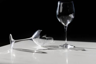 Kırık şarap kadehi, gölgeli minimalizmin beyaz arka planının yanında. Minimalizmin gölgeli beyaz arka planının yanında yüksek kaliteli fotokırık şarap kadehi.