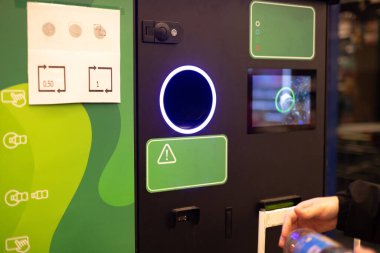 İnsan eli makineye plastik şişe koyar. Müşteriler biberonlarını ve kutularını geri veriyorlar. Yüksek kalite fotoğraf