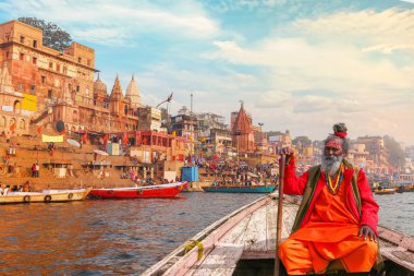 Sadhu baba, 24 Aralık 2018 tarihli antik şehir mimarisi manzaralı Varanasi Ganj Nehri 'nde tekne turunun tadını çıkarıyor.