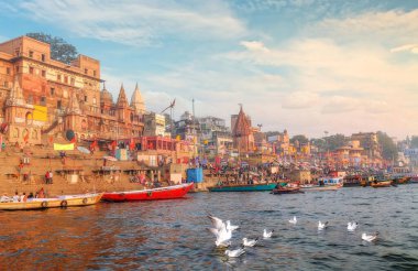 Varanasi antik şehir mimarisi gün batımında Ganj nehrindeki göçmen kuşların görüntüsüyle