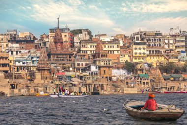 Varanasi şehri mimarisi. Tahta bir teknede Hint sadhu 'su var.
