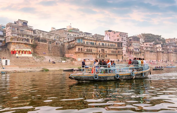 Turistler, tarihi kent mimarisi manzarasıyla gün batımında Varanasi Ganj Nehri 'nde tekne turunun keyfini çıkarıyorlar.
