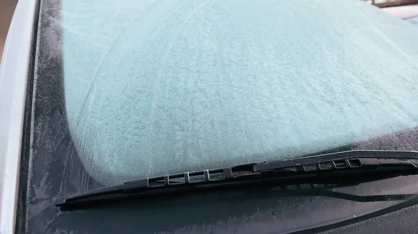 Dondurucu bir kış sabahında arabanın ön camının buzla kaplı olduğu yakın plan görüntüsü. Mevsimsel hava koşulları soğuk sıcaklıkları ve günlük sürüş zorluklarını vurguluyor.