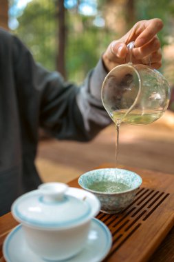 Geleneksel Çin çay seremonisi, seramik bir kaseye oolong çayı dökmek. Geleneksel Çin Kung Fu çay seremonisinin yakın çekimi. Bir çaydanlık kil çaydanlıktan basit bir seramik fincana kokulu oolong çayı dökülüyor. Sakin ve düşünceli bir an..