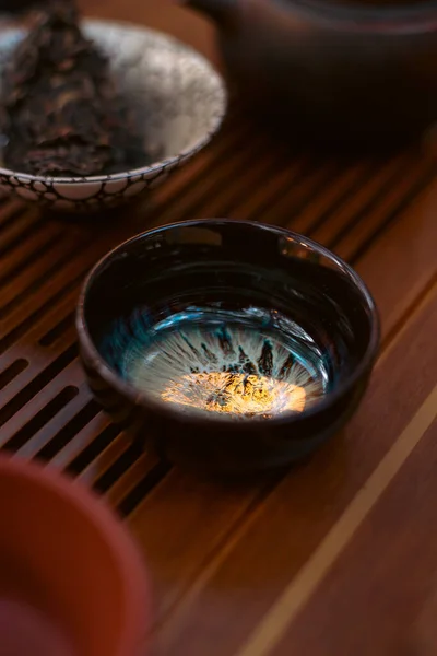 Geleneksel çay seremonilerinde kullanılan küçük seramik çay fincanının minimalist yakın çekimi, basitliği, dokuyu, işçiliği ve dikkatli çay içmenin sakin estetiğini vurgulamak..