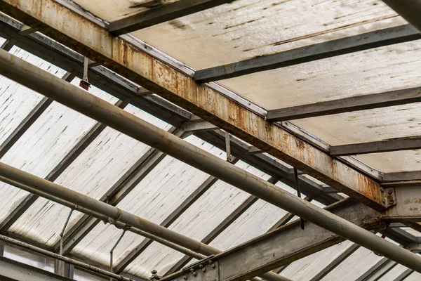 metal and glass roof of a greenhouse with pipes