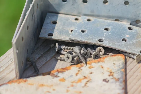 close up of construction instruments- metal corners, screws on wooden work bench outdoors