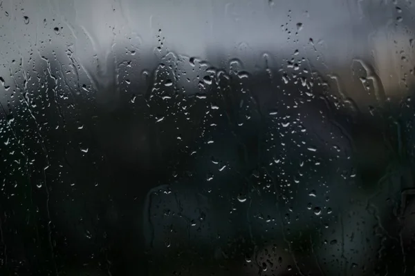 Rain drops on dark window glass. Abstract background texture.