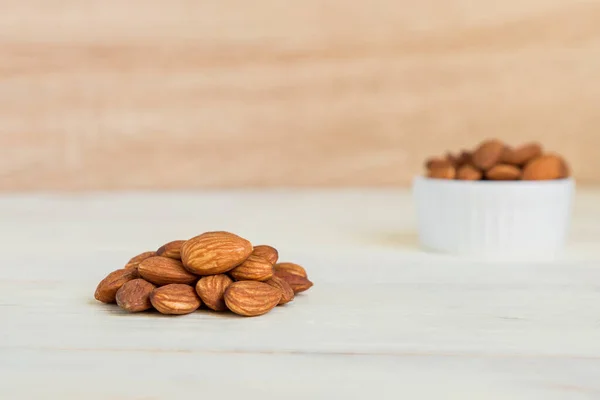 Pile of Roasted Almonds on white wooden table, close up, copy space