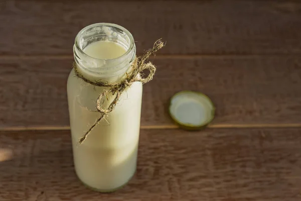 Open bottle of fresh milk on wooden background. Natural dietary product.