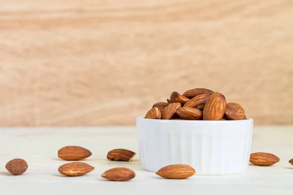 Roasted Almonds in white porcelain bowl on white wooden table