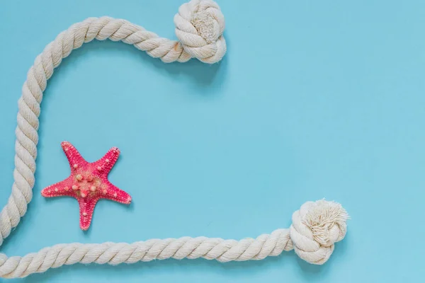 Red starfish and knot rope on light blue background with copy space. summer holiday and vacation concept