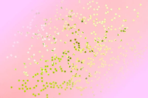 Gold star glitter on pink pastel background. Festive concept. Place for design.