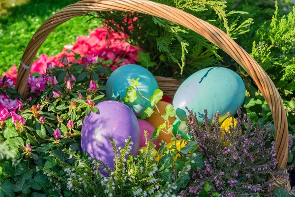 Easter street decoration. Wicker basket full of painted easter eeggs, cake and flowers.