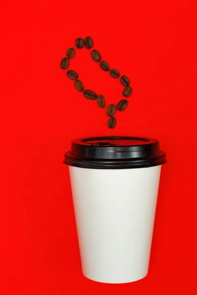 take away coffee cup on colorful red paper background. Steam made of coffee beans