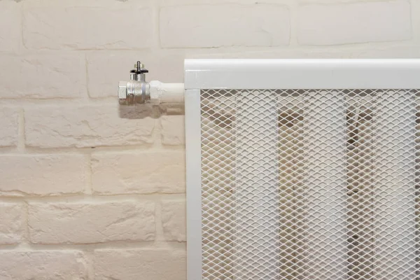 radiator heating device against a white brick wall. cozy house with modern interior room close up