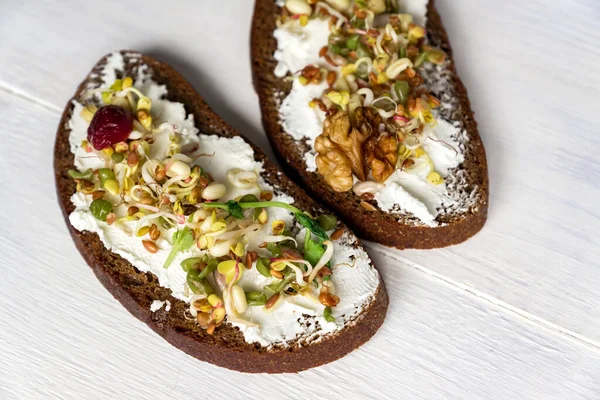 Healthy macrobiotic breakfast. Sandwich with cream cheese, peas microgreens and sprouted mung beans, walnut, sunflower and flax on wooden background. vegan, raw food diet