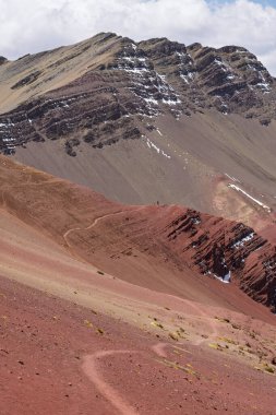 Kızıl Vadi 'nin canlı kırmızı ve kahverengi mineral tabakalarının yüksek açılı görüntüsü. Gökkuşağı Dağı, Peru And Dağları yakınlarındaki uçsuz bucaksız yamaçlarda dar bir yürüyüş yolu rüzgarları esiyor..