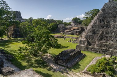 Tikal Ulusal Parkı 'ndaki çimenli Büyük Plaza manzarası. Guatemala' da 2. Tapınak, Maskeler Tapınağı ve orman tepe örtüsü yer alıyor..