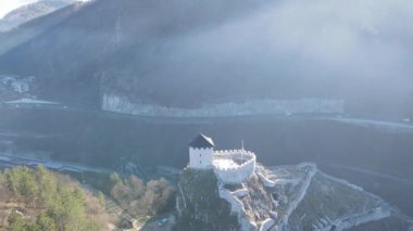 Antik, minyatür bir kalenin etrafında dairesel bir dron uçuşunu gösteren çarpıcı bir zaman makinesi videosu yüksek bir kaya kulesinin tepesine tünemiş. Bu sinematik hava, yapının görkemli izolasyonunu ve tarihsel ihtişamını yansıtıyor..