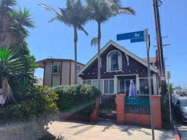 Uzun palmiye ağaçları tarafından çerçevelenmiş mor zanaatkar tarzı bir evin olduğu büyüleyici bir ev. Sessiz mahallede yemyeşil verimli bir ortam var. Rahat bir Güney-Kaliforniya atmosferi yaratıyorlar.