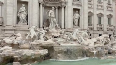 Roma, İtalya - 03 Ocak 2026: Roma şehir manzarası tarihi mimari ve ön planda zarif bir çeşme ile. Sıcak güneş ışığı klasik binaları vurguluyor ve zamansız bir İtalyan atmosferi yaratıyor..