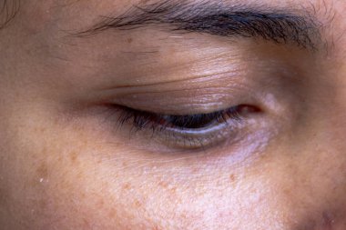 Kapalı bir insan gözünün makro yakın çekimi doğal deri dokusunu, kirpikleri ve kaş detaylarını vurguluyor, güzelliği, sakinliği ve özgünlüğü vurguluyor..