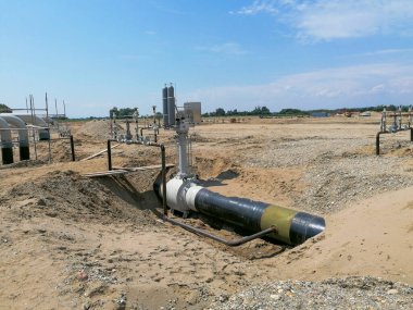 Geniş doğal gaz boru hattı ve sanayi kapakçığı kurulumu açık arazideki bir inşaat sahasında, enerji altyapısının gelişimini ve mühendislik çalışmalarını gösteriyor.