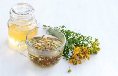 Şeffaf bir fincan dolusu taze Hypericum sarı çiçekli St. John otlu içecek. Bahar balı kavanozu. Alternatif Tıp ve Homeopatik İlaçlar için şifalı bitkiler