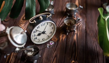 Kahvaltıda. Eski bir kahve demliğinden el yapımı kahve. Eski bir çalar saatin yanında gümüş bir kupa.