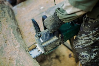 Kamuflaj kalın ahşap testere testere adam. Toz içecek uçan