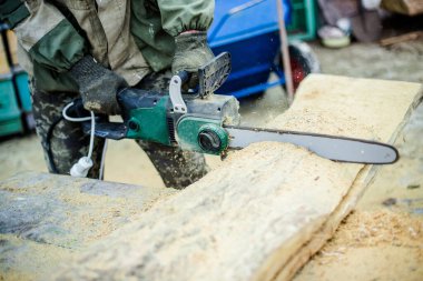 Testereler el testeresinde. Adam kalın bir tahta parçası kesiyor. Uçan testere parçalarından.