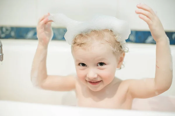 girl has bath foam bubbles on head. hygiene procedures. Personal hygiene of children under two year. Bathing toddlers in shared bathroom