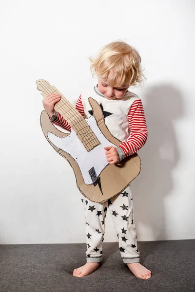 music school classes. little funny girl with DIY guitar. musical instrument handmade of cardboard in hands of child