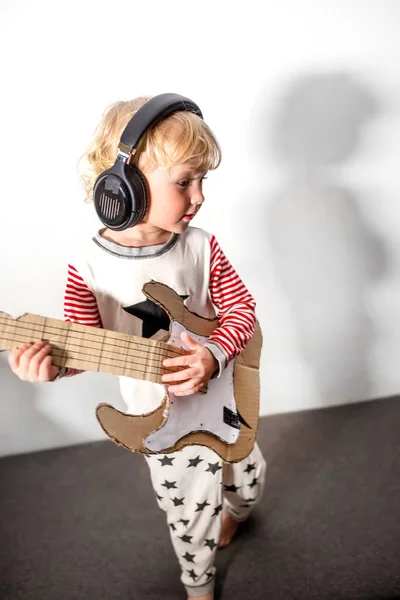 my guitar. girl playing guitar. musical instrument handmade of cardboard in hands of child. musical school concept