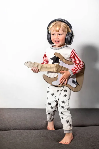 happy singer with guitar. little funny girl with DIY guitar. musical instrument handmade of cardboard in hands of child. musical school concept.