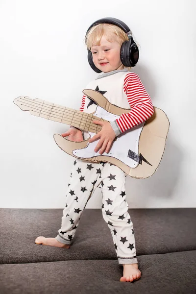 guitar player or guitarist. little funny girl with DIY guitar. musical instrument handmade of cardboard in hands of child. musical school concept. country music