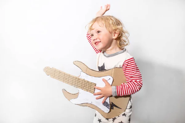 have fun on party. little funny girl with DIY guitar. musical instrument handmade of cardboard in hands of child. Learning to play the guitar. musical school concept