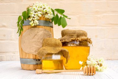 Mesaj at tatlım. Hasat 2021. Balpeteğinde bal, çevre dostu akasya nektarı ile ahşap bir fıçı, arıcılık ile dolu cam kavanozlar.