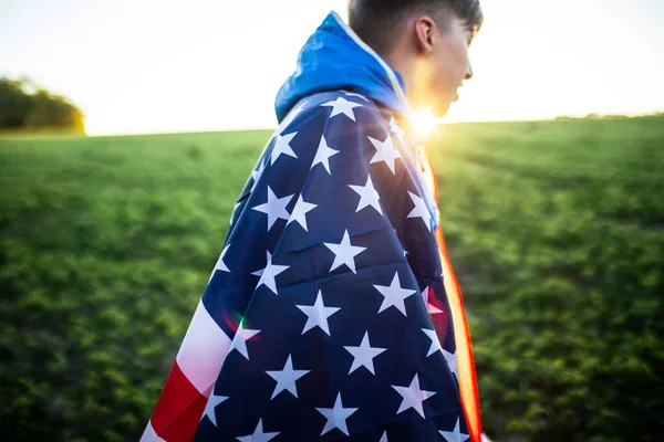 boy threw Flag of America on shoulders. flag of america USA at sunset outdoors. Independence Day. Constitution day. Happy Teen