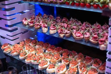 Hazır atıştırmalıklarla yemek servisi. Kanepeler servis masasında. Ekmeğin üzerinde jambon dilimleri. Açık büfe partisi için tabak süsleme. Ziyafet servisi. yemek servisi.