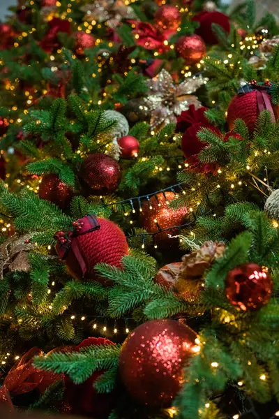 Noel ağacındaki kırmızı oyuncak topları süslenmiş. Oyuncak ve ışıklarla donatılmış arka plan
